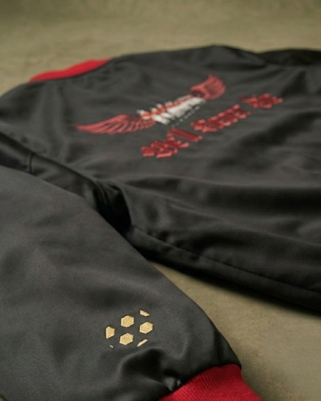 Black jacket with red and gold embroidery on a beige surface