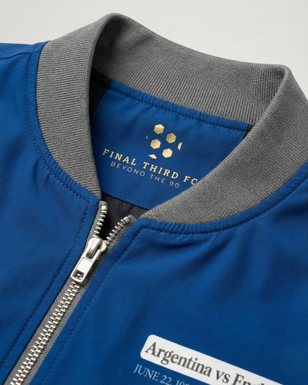 Blue jacket with gray collar and visible branding on a light gray background
