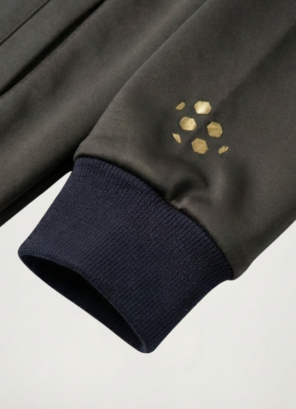 Close-up of a dark green sleeve with gold hexagonal patterns on a light gray background