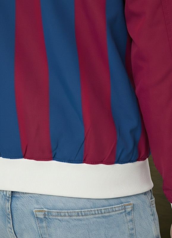 Close-up of a jacket with red and blue stripes worn over jeans.