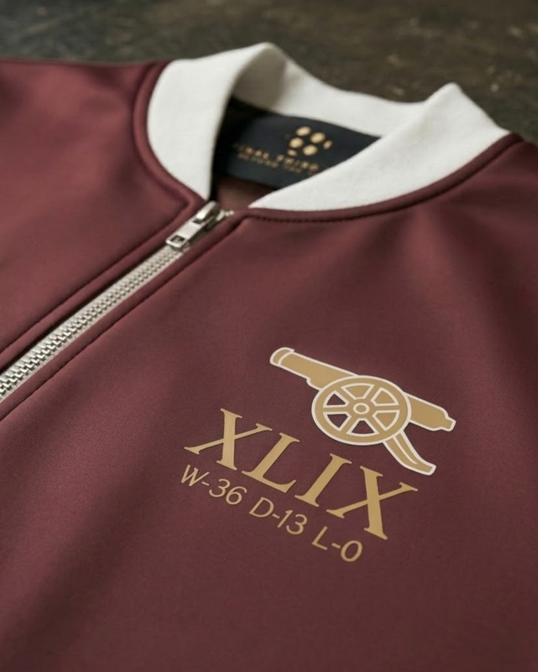 Maroon jacket with gold logo and text on a dark background