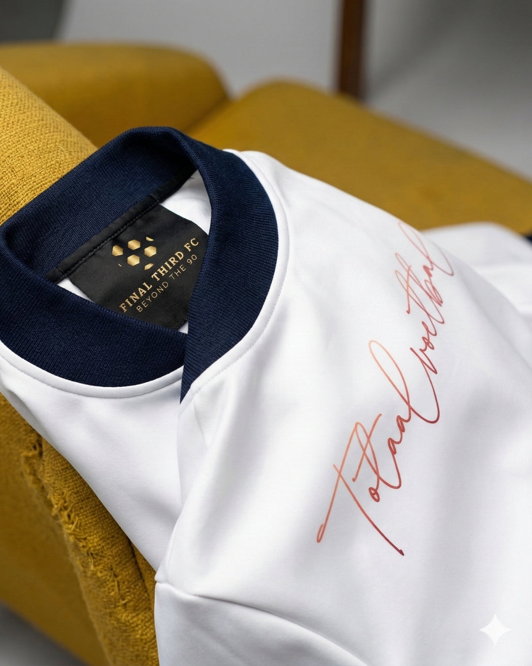 White shirt with navy collar and red text on a yellow surface